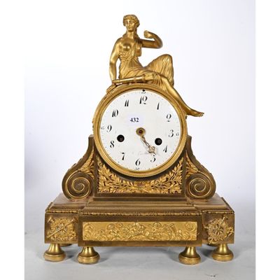 une horloge en or avec une femme assise dessus
