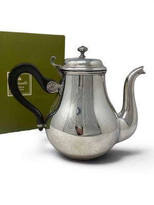 the teapot is silver with a black handle and a green box