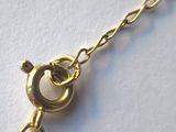 gold plated chain bracelet with a heart charm on a white background