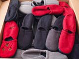 de nombreuses paires de chaussons dans une boîte posée par terre