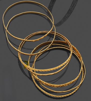 un lot de cinq bracelets en or posés sur un fond noir