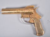 a gold gun that is sitting on a white surface