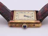 a watch with a gold case and a blue stone in it