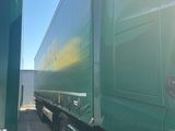 two green semi trucks parked side by side in a parking lot