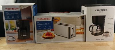 trois boîtes posées sur la table, à côté d'une cafetière et d'un grille-pain