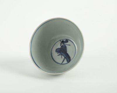 une tasse bleue et blanche sur laquelle est représenté un oiseau