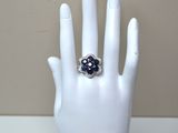 a white hand with a ring on it that has a blue flower on it