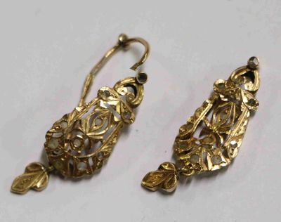 deux paires de boucles d'oreilles en or posées sur une surface blanche
