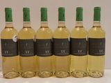 six bottles of white wine are lined up on a table