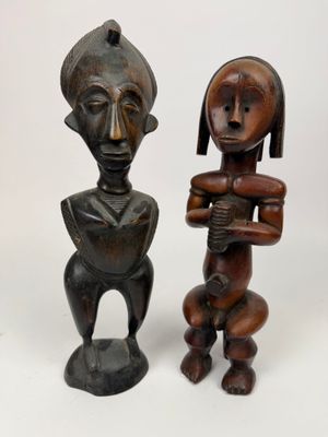 deux statues en bois représentant une femme et un homme sur fond blanc