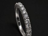 a white gold ring with round brilliant cut diamonds on a black background