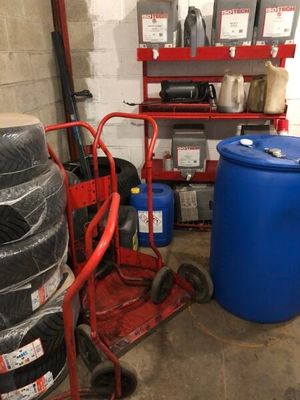 a red cart that is next to a stack of blue barrels