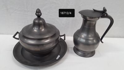 a silver pitcher and a silver plate on a white table