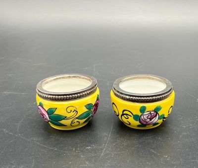 pair of yellow glass jars with floral designs on them sitting on a table