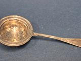 une cuillère ancienne en argent avec un manche, posée sur un fond bleu