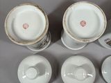 three cups and a saucer sitting on top of a white table