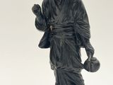 une statue noire représentant un homme tenant un sac