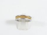 un gros plan d'une bague en argent et en or posée sur une surface blanche