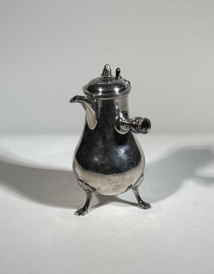 a small silver teapot sitting on a white table