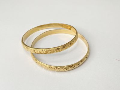 a pair of gold rings on a white surface