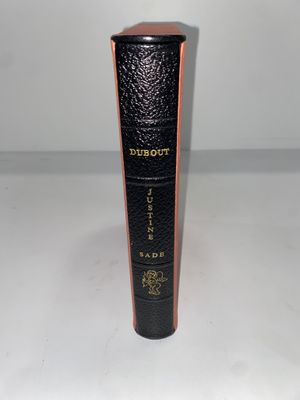 un vieux livre noir orné de lettres dorées, posé sur une surface blanche