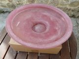 a pink bowl sitting on top of a box on a wooden table