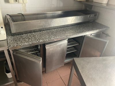 plan de travail en acier inoxydable dans une cuisine professionnelle, équipé d'un évier et d'un réfrigérateur