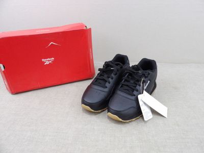 pair of black and gold running shoes next to a red shoe box