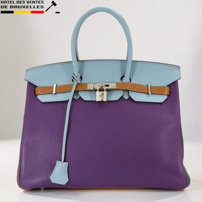 un sac à main violet et bleu posé sur une table blanche