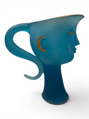 un vase bleu sur lequel est représenté un visage sur le côté