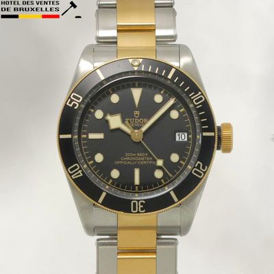 une montre noire et dorée montée sur un bracelet argenté et doré
