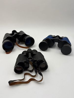 three pairs of binoculars sitting on top of a white surface