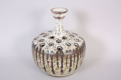 a white and brown vase sitting on a white surface
