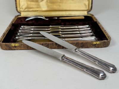 cinq pièces d'argenterie dans un coffret posé sur une table
