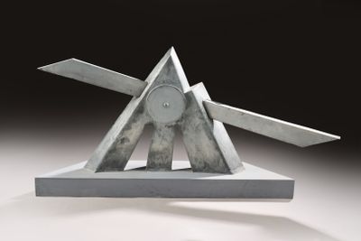 une sculpture métallique représentant un triangle surmonté d'une paire de ciseaux