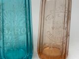 two different colored glass bottles sitting next to each other