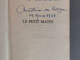 un livre ouvert, sur lequel est posée une note manuscrite, posé sur une table
