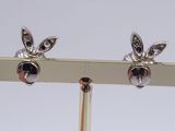 pair of silver earrings on a gold stand with a white background
