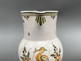 a white vase with a bird on it sitting on a table