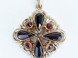 a close up of a black and red pendant on a white surface