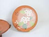a small plate with flowers painted on it next to a small bowl