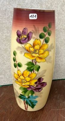 un vase avec des fleurs peintes dessus, posé sur une table