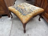 un petit tabouret recouvert d'une tapisserie