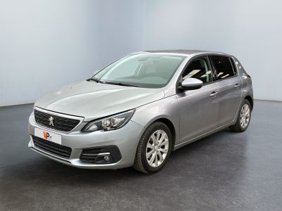 La voiture argentée est garée dans une grande pièce au sol noir.