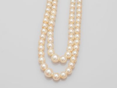 a close up of two strands of pearls on a white surface