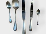 five spoons, a knife, and a spoon on a white surface