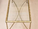 une table basse en verre avec une structure en métal doré et un plateau en verre