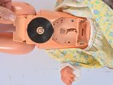 a person holding a doll with a record in it ' s hand
