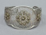 an image of a silver bracelet with a flower design on it
