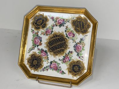 une assiette décorée d'or et de blanc, ornée de fleurs